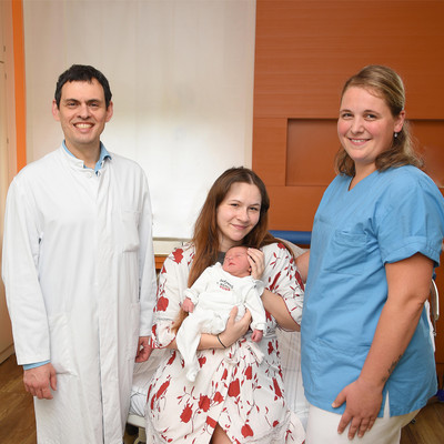 Chefarzt Dr. med. Michael Anapolski und Hebamme Lisa Klein freuen sich mit Mama Angelika über die Geburt der kleinen Aurelia 